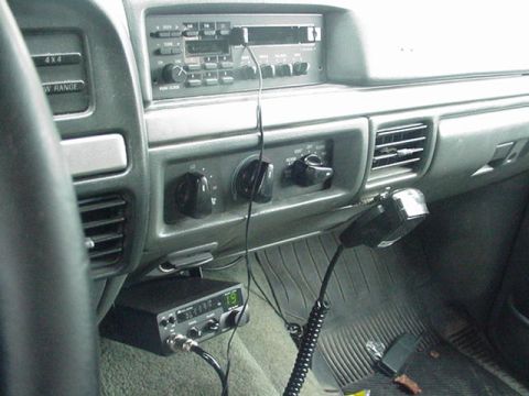 1993 Ford Bronco - The interior of a vehicle shows the dashboard, radio, and a CB radio unit with its microphone attached.