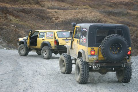 2003 Jeep TJ - Two yellow Jeeps, a 2003 TJ and a Cherokee, travel on a dirt road.