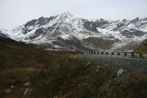 2003 Jeep TJ - A scenic mountain road passes through a landscape with snow on the peaks and brown vegetation on the hills.
