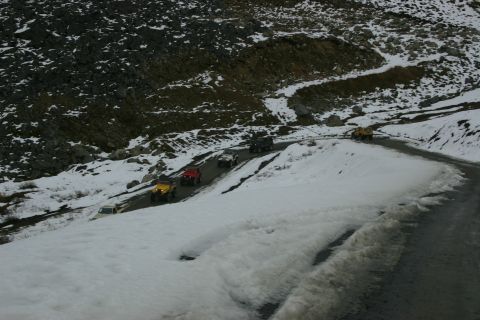 2003 Jeep TJ - Several off-road vehicles navigate a treacherous, snow-laden mountain pass.