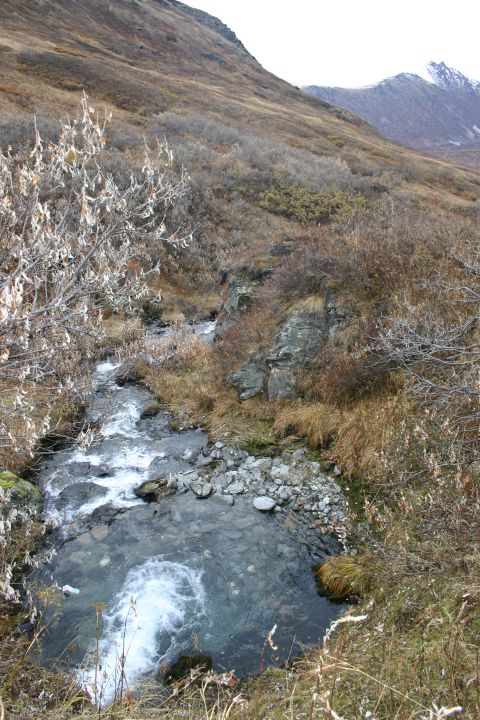 2003 Jeep TJ - A clear mountain stream winds through a rocky landscape under a cloudy sky.