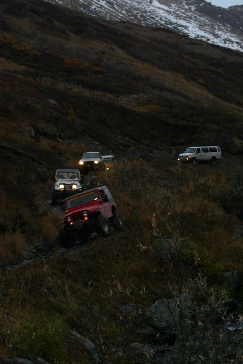 2003 Jeep TJ - Multiple off-road vehicles navigate a challenging mountain trail during twilight.