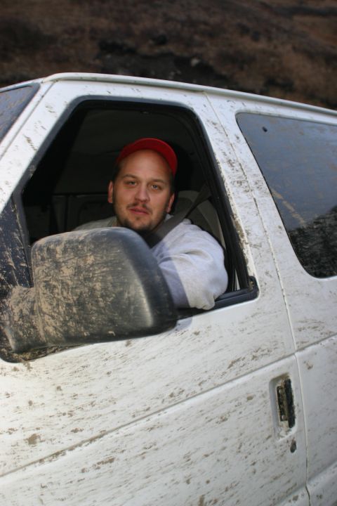 2003 Jeep TJ - Mud-splattered white van with a man wearing a red cap visible through the driver's side window.