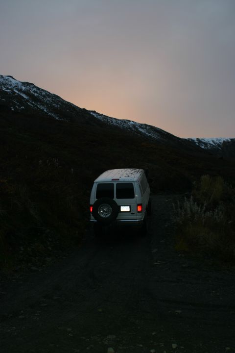 2003 Jeep TJ - A white van travels on a dirt road through a mountainous landscape as dusk settles.