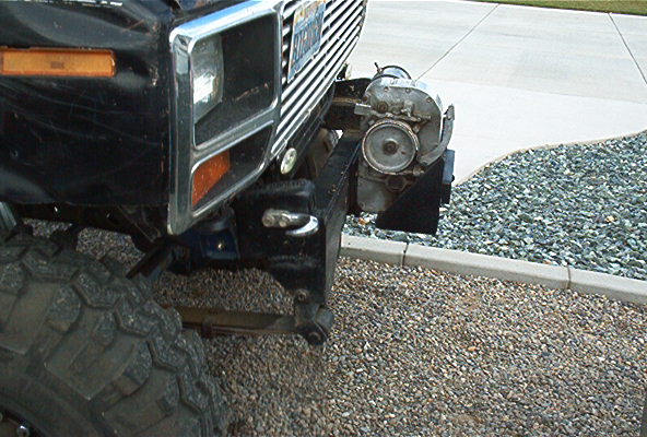 Front of a black Ford Bronco with a winch mounted on the bumper. Large off-road tire visible