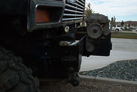 1986 Ford Bronco - A close-up of a vehicle's front bumper and grille, with a winch attached, and another vehicle visible in the distance.
