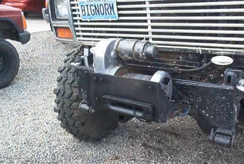 1986 Ford Bronco - Front view of a 1986 Ford Bronco equipped with a winch, next to another vehicle.