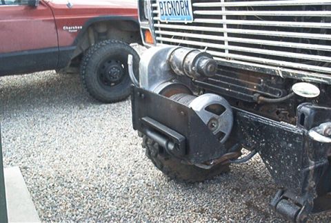1986 Ford Bronco - A winch is mounted to the front of a truck, with a red Jeep Cherokee visible in the background.