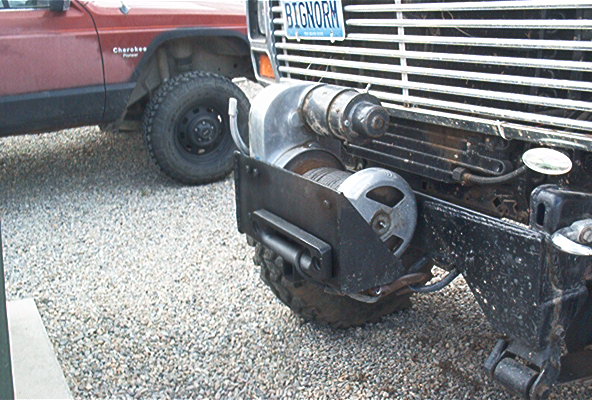 Front of a truck with a winch mounted, and a red Jeep Cherokee behind it