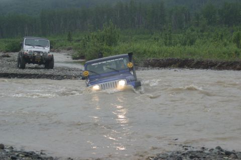 2003 Jeep TJ - Two Jeeps navigate a shallow river, with the lead vehicle, a blue 2003 Jeep TJ, splashing through the water.