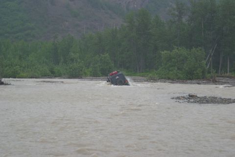 2003 Jeep TJ - A Jeep TJ navigates a river crossing, its tires submerged in the murky water.