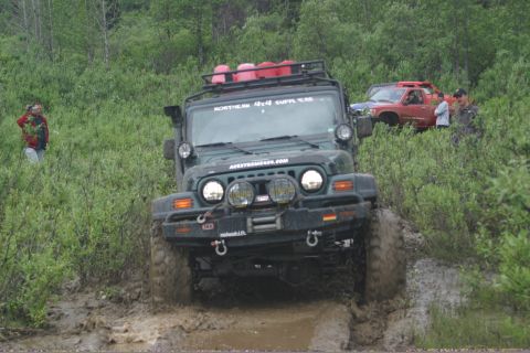 2003 Jeep TJ - Jeep TJ navigates a muddy trail with another vehicle visible in the background.