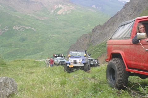 2003 Jeep TJ - A group of off-road vehicles, including a red SUV and a blue Jeep TJ, navigate a scenic mountain trail.