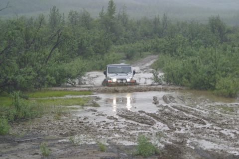 2003 Jeep TJ - A Jeep Wrangler navigates a challenging muddy terrain, kicking up water and mud as it drives through a puddle.