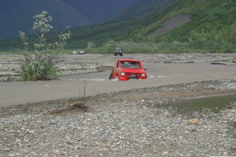 2003 Jeep TJ - Multiple off-road vehicles navigate a rocky riverbed in a mountainous landscape.