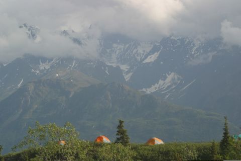 2003 Jeep TJ - Tents are pitched on a ridge with a backdrop of misty, snow-covered mountains.