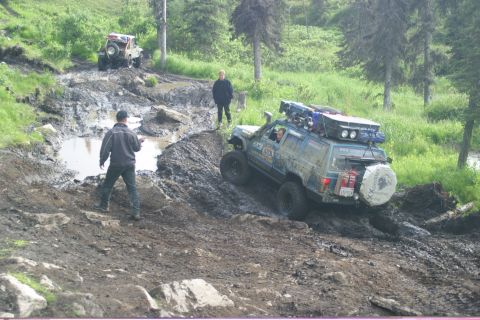 2003 Jeep TJ - Two off-road vehicles tackle a challenging muddy terrain, with one SUV equipped for an expedition.