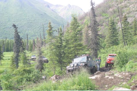2003 Jeep TJ - Multiple Jeeps navigating a challenging off-road trail in a mountainous, wooded area.