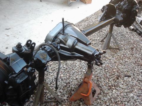 1978 Ford Bronco - Vehicle axle assembly, likely undergoing restoration or repair, is supported by jack stands.