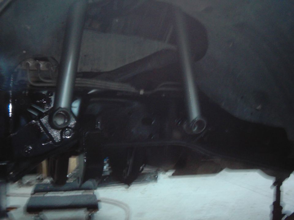 Undercarriage of a vehicle with black painted suspension components and shock absorbers visible