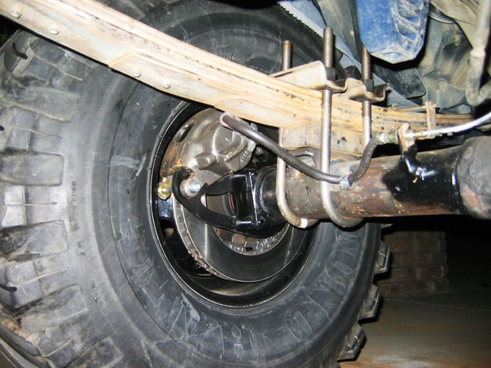Rear axle underside with leaf spring, U-bolts, differential, driveshaft and off-road tire