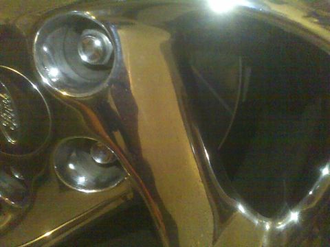 1996 Ford Probe - Close-up of a chrome wheel, showing lug nut recesses and a partial Ford emblem.