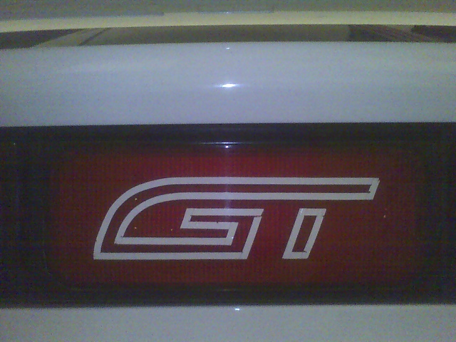 White GT emblem on a red panel. Supermotors.net watermark visible