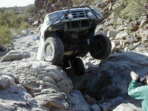 1993 Ford Bronco - A white 1992 Ford Bronco tackles a challenging rocky terrain, demonstrating its off-road capabilities.