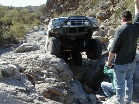1993 Ford Bronco - A modified Ford Bronco navigates a rocky trail with two onlookers.
