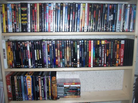 1995 Ford Bronco - A collection of DVDs is organized on wooden shelves, with a few stacked horizontally on the bottom shelf.