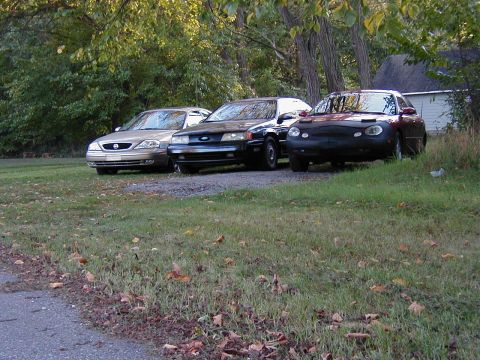 1990 Ford Taurus - A 1990 Ford Taurus is parked in front of other vehicles on a gravel lot.
