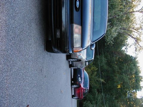 1990 Ford Taurus - A black 1990 Ford Taurus is parked in a line with other vehicles.