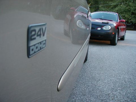 1990 Ford Taurus - A car door with a 24V DOHC badge is parked next to another vehicle.