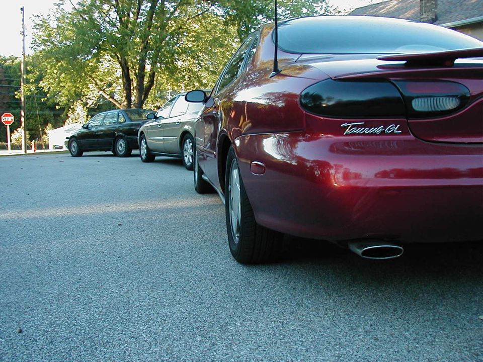 Rear of a red 1990 Ford Taurus GL with two other cars behind it