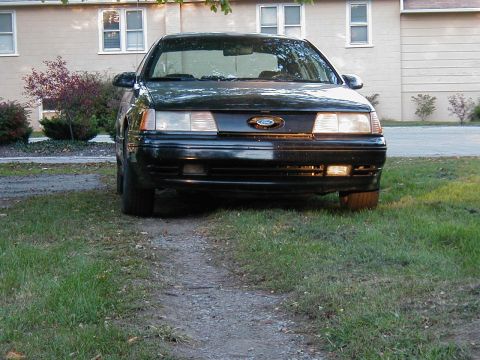 1990 Ford Taurus - This black 1990 Ford Taurus is seen from the front, parked in a grassy area.