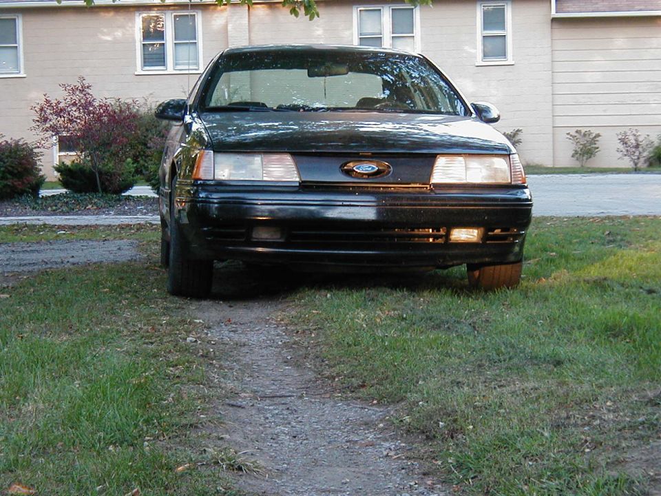 Front view of a black 1990 Ford Taurus parked on grass