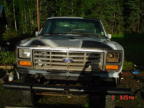 1986 Ford F-150 - Front view of a Ford F-150 truck, likely from the early 1980s, with camouflage paint and a missing headlight.