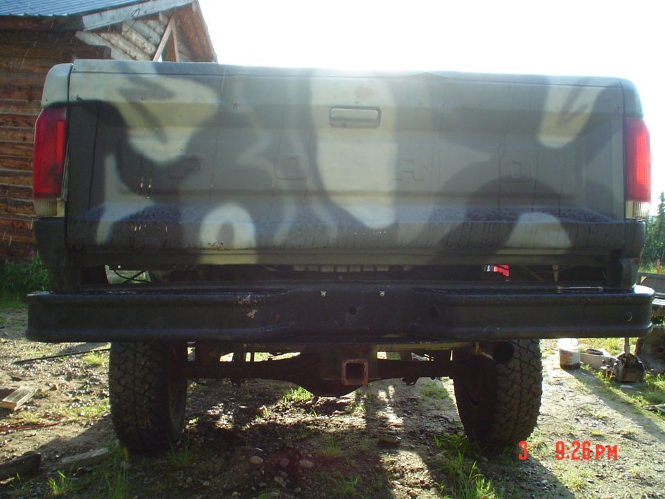 Rear of camouflage pickup truck with black bumper and tow hitch