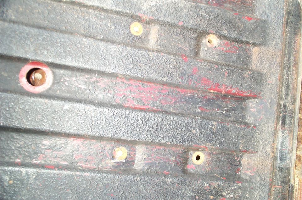 Close-up of a truck bed with tie-down points and some red paint showing through the black coating