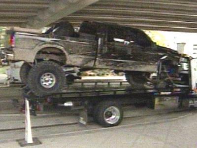 1993 Ford Bronco - A damaged black pickup truck is loaded onto a flatbed tow truck.
