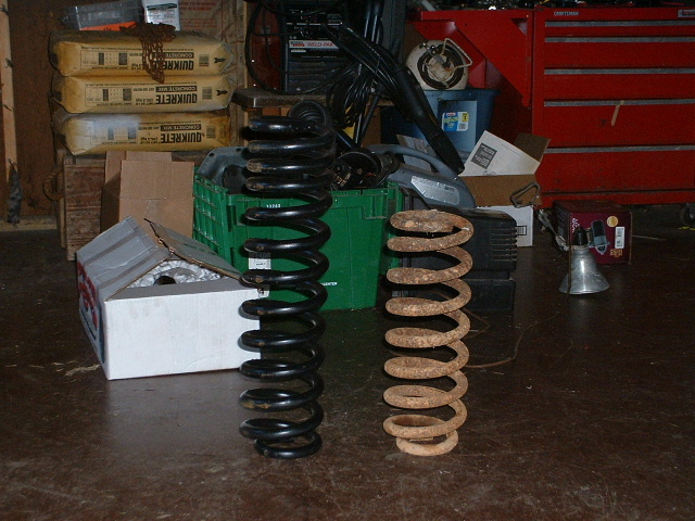 New black coil spring next to rusty coil spring