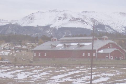 1972 Ford Ranchero - A rural scene a large red barn with snow-covered mountains in the distance and a pickup truck on a road.