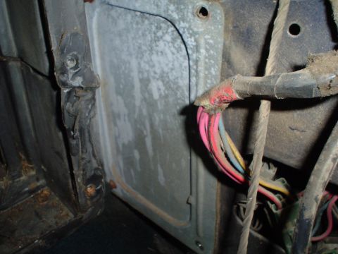 1984 Ford Bronco - A close-up view of the interior wiring harness and a metal panel within a vehicle.