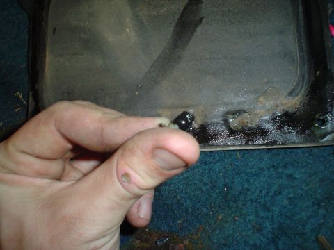 1984 Ford Bronco - Close-up of a hand holding a bolt, with a dirty metal surface in the background.