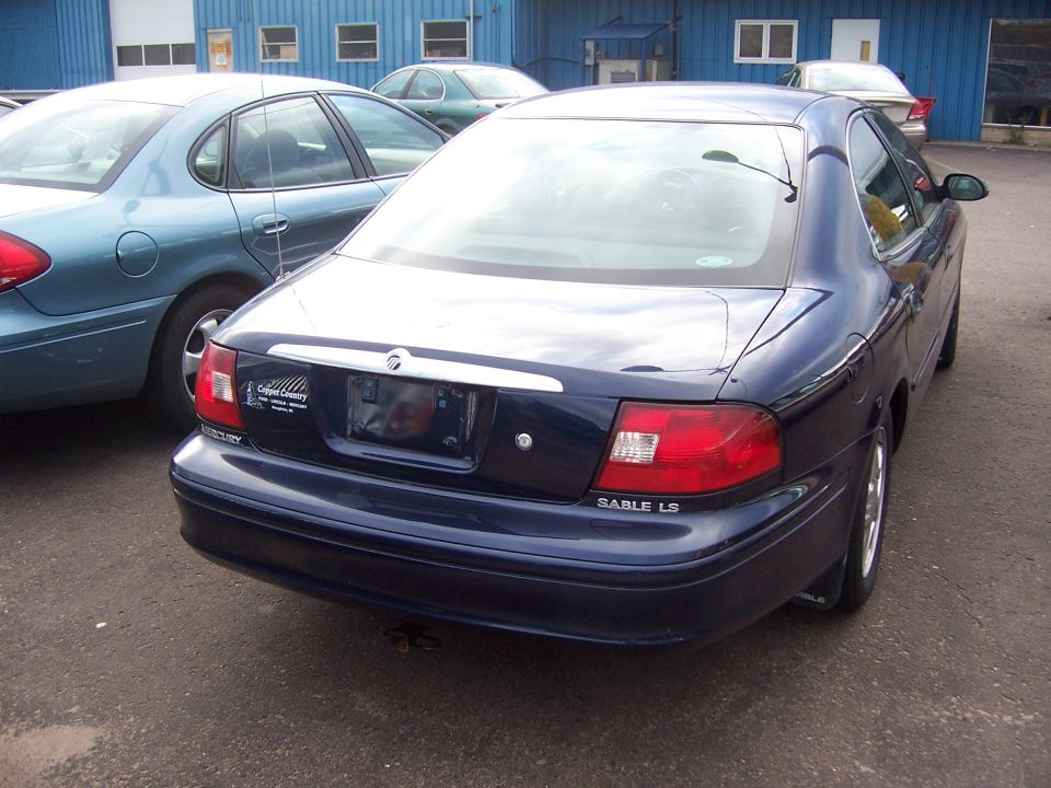 Dark blue Mercury Sable LS sedan seen from the rear in a parking lot with other cars