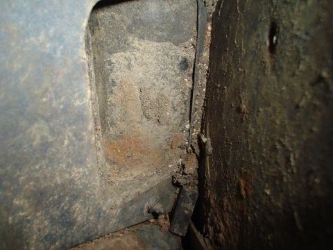 1984 Ford Bronco - Detail of rust and dirt accumulation on the interior body panel and frame, suggesting wear and tear.