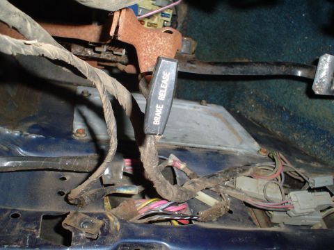 1984 Ford Bronco - The photo shows the brake release lever and a complex wiring harness within a vehicle's interior.