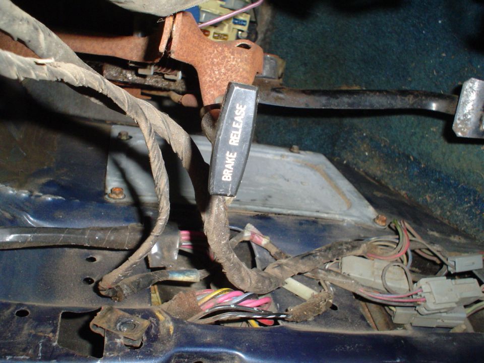 Close-up of vehicle interior showing brake release lever and tangled wiring harness