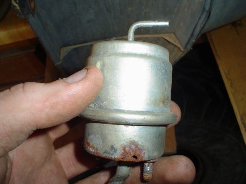 1984 Ford Bronco - A hand holds a metal vacuum actuator, a component likely from a vehicle's engine or emissions system.