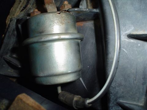 1984 Ford Bronco - A close-up view of a vehicle's fuel pump relay, showing its metallic casing and electrical connections.